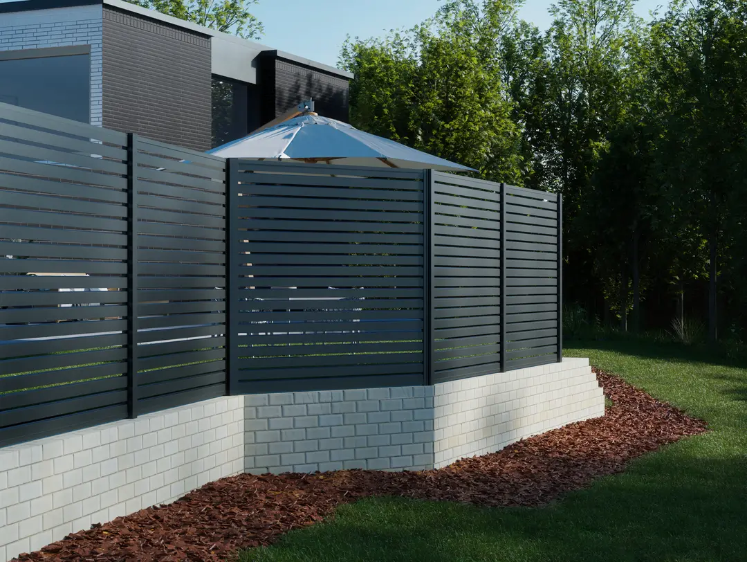 Kit d'angle pour poteau The BOSTON pivot + quincaillerie, métal, monté sur clôture noire avec poteaux carrés devant un mur de briques blanches et paillis.