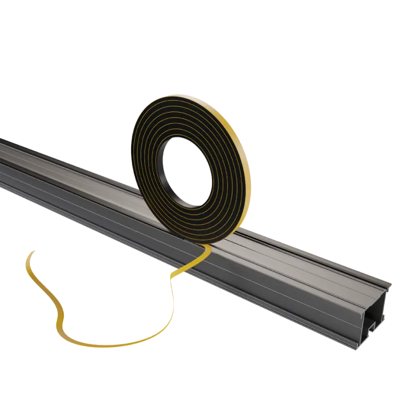 Rouleau de ruban adhésif double face partiellement déroulé près d'un profilé noir long, matériau indéterminé, sur fond blanc.