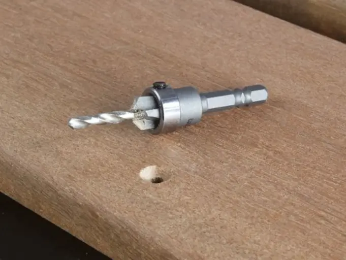 Foret à chanfreiner Cobra® diam. 4mm posé sur planche bois, à côté d'un trou fraisé visible.