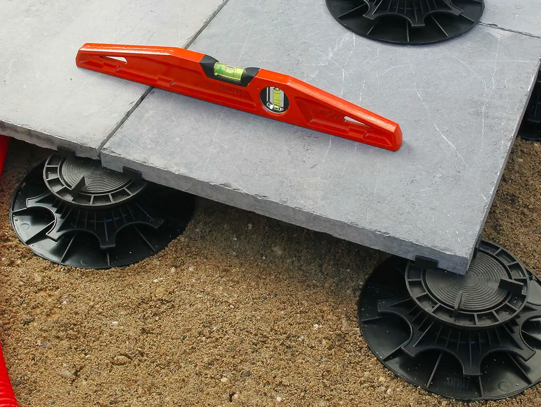 Niveau à bulles Plot NIVO H140-230mm sur dalle, posée sur plots plastiques réglables au-dessus d'un lit de sable compacté.